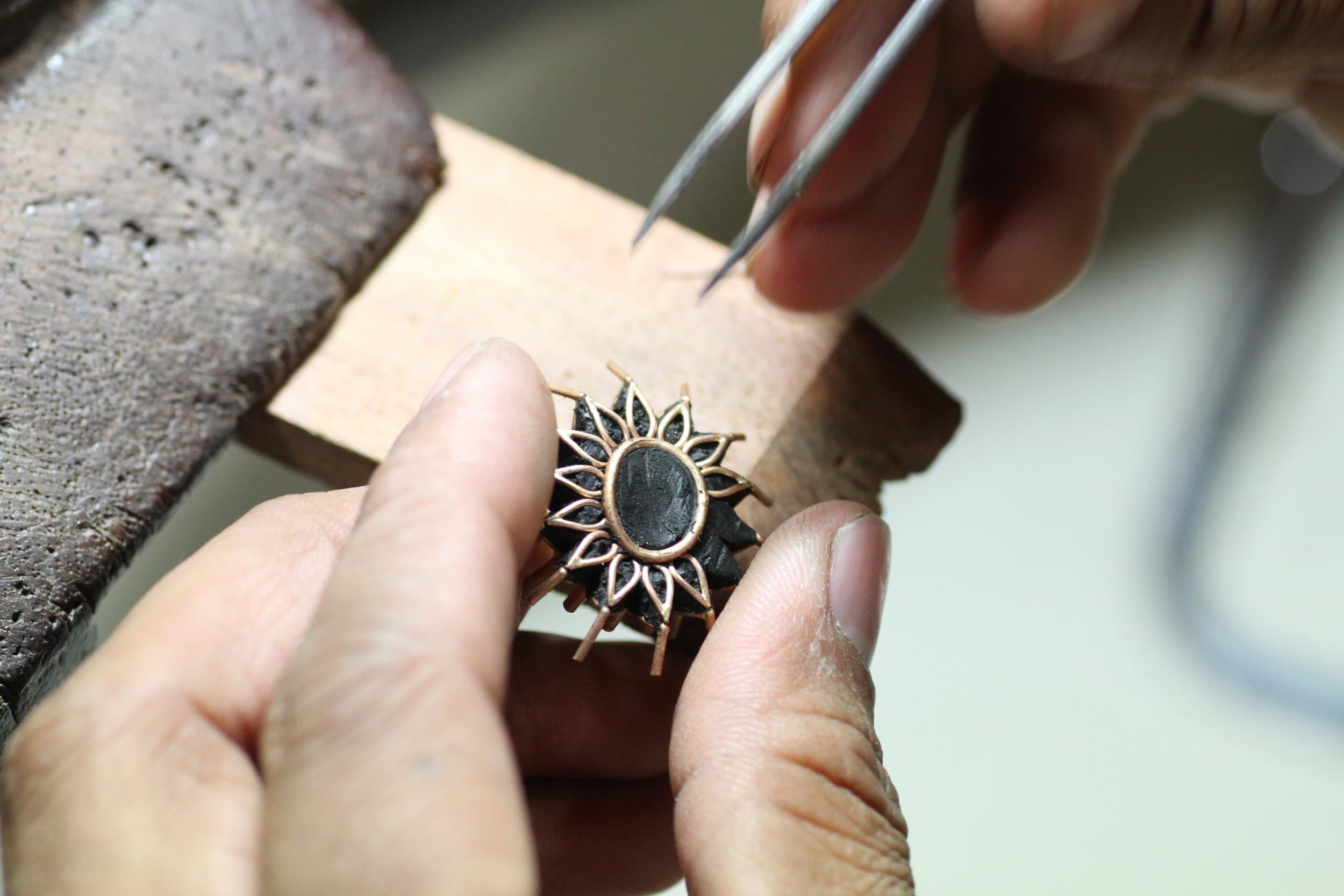 Las manos de un artesano engastando una montura de oro en el banco, taller de Sitapura