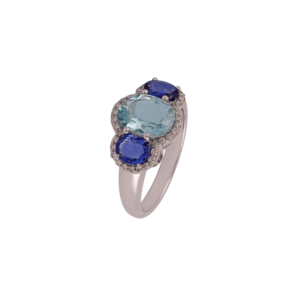 Anillo de oro blanco con un óvalo azul pálido entre dos zafiros azul intenso, los tres con halo de diamantes