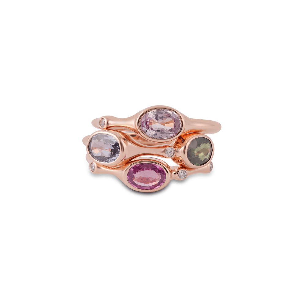 Four stacked narrow rose gold rings each set with a bezelled coloured sapphire