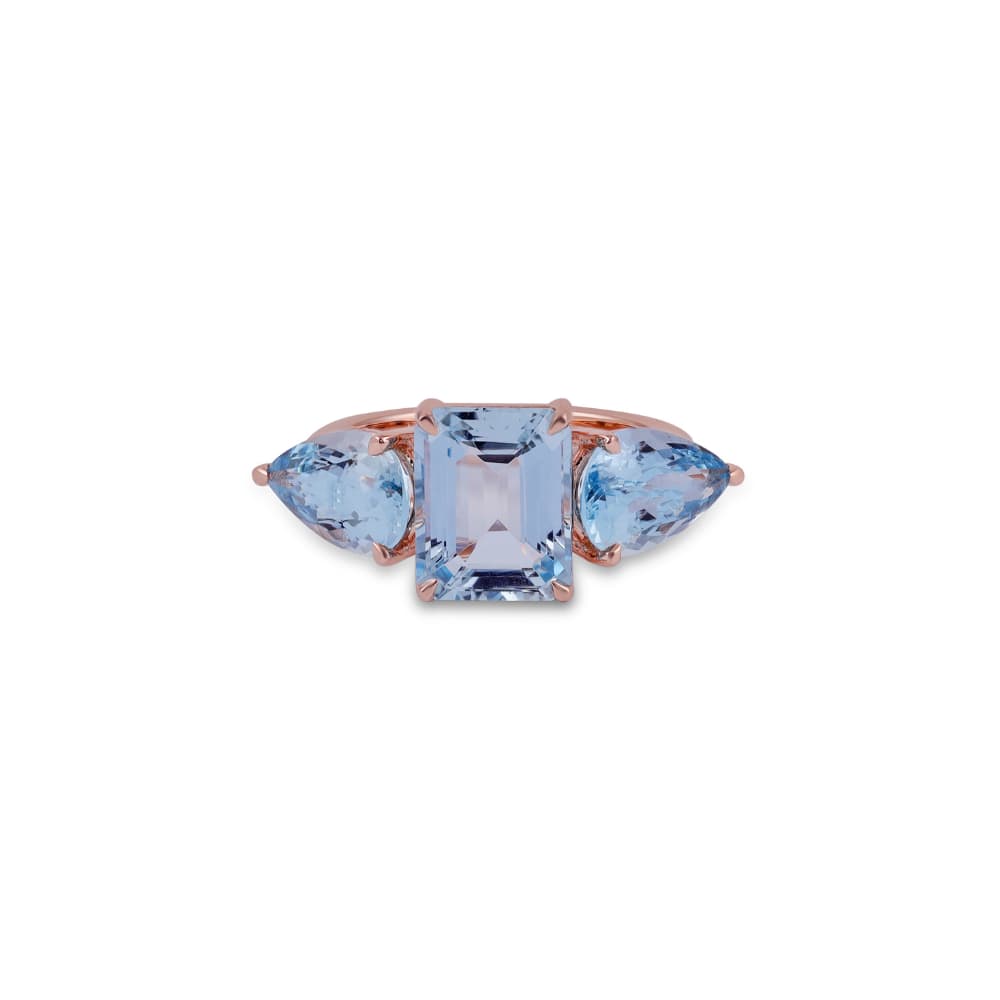 Anillo de oro rosa con una piedra azul pálido de talla esmeralda flanqueada por dos piedras talla trillón
